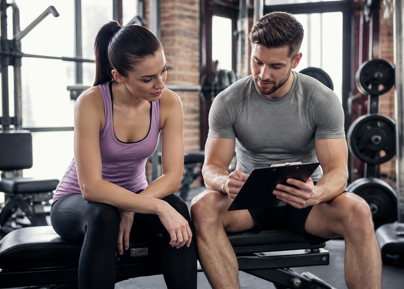 Coach and client reviewing goals on a clipboard during a gym consultation